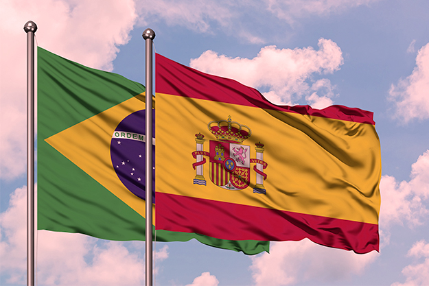 Bandeira do Brasil sobreposta com a bandeira da Espanha com um céu azul de fundo no processo de tradução juramentada