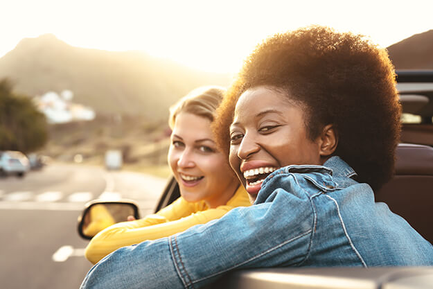 duas mulheres sorrindo após alugar carro em outro país