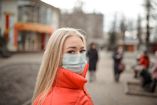 jovem loira de máscara a viajar na pandemia