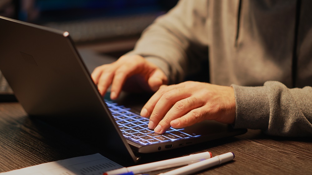 Tradutor profissional realizando uma tradução juramentada de documentos em seu notebook.